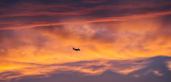 Airplane Flying Against Colorful Sunset Glow Sky